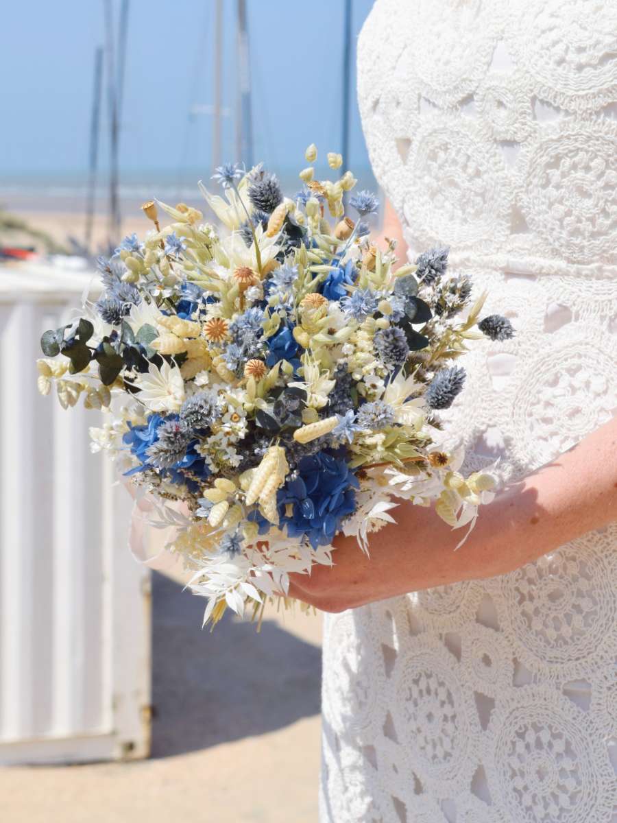 Close-up van een modern en klein trouwboeket van droogbloemen, rond gebonden en gemaakt van blauwe hortensia, witte ruscus en groene papaver