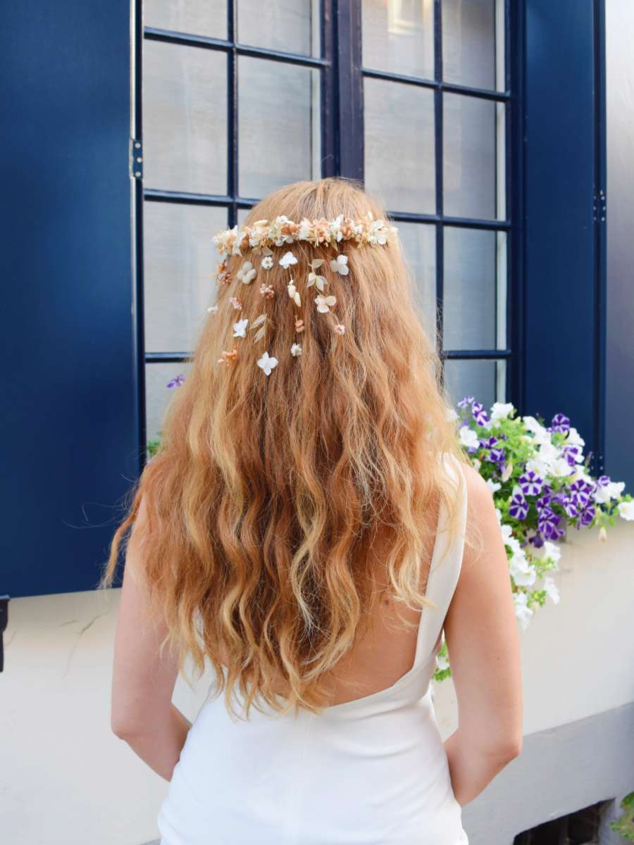 bruid met lang los haar draagt bloemenkroon van droogbloemen met afhangende bloemetjes