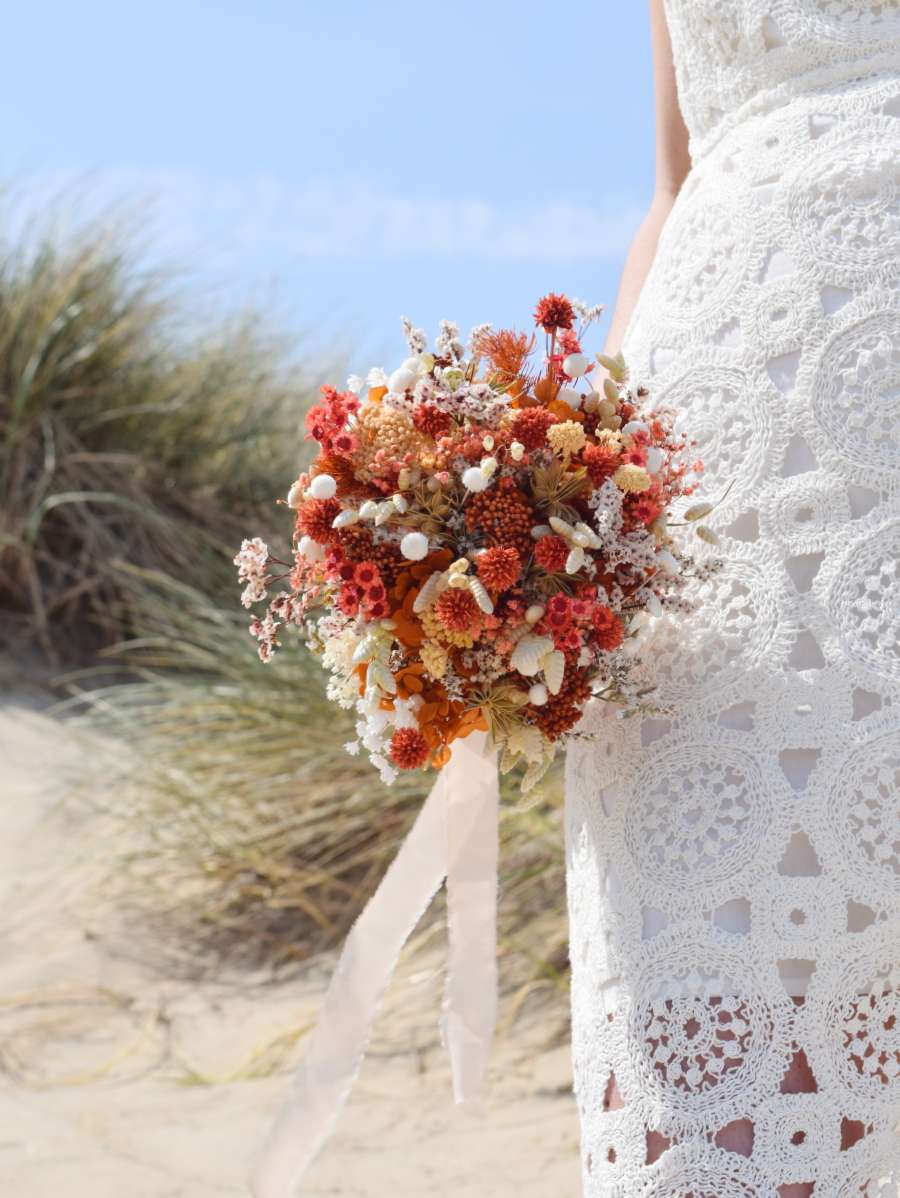 Close-up van elegant en klein trouwboeket van droogbloemen in frisse tinten met een lang lint aan gebonden