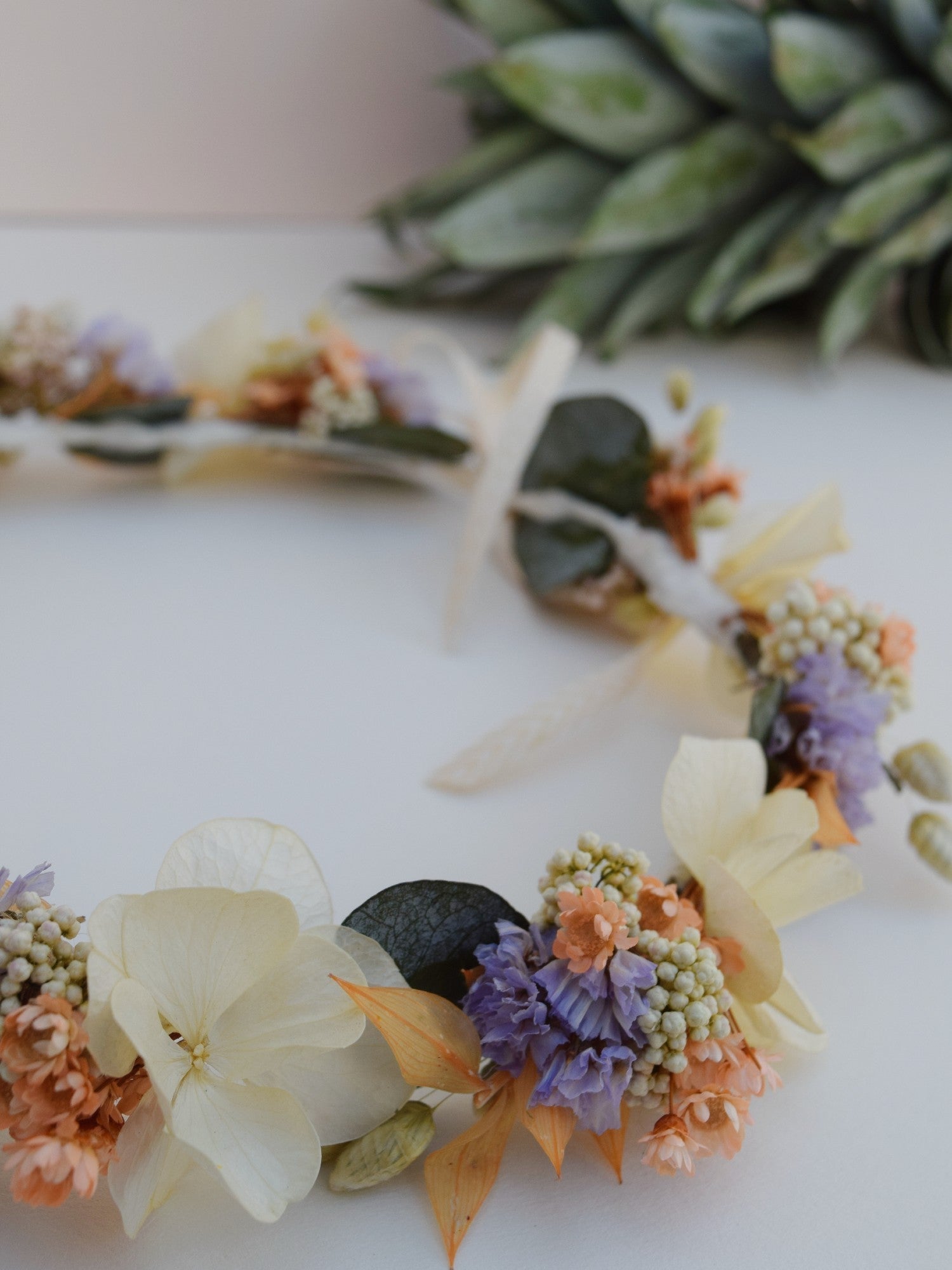 bloemenkroon voor een kind gemaakt van droogbloemen zoals hortensia, eucalyptus en paarse, oranje droogbloemen