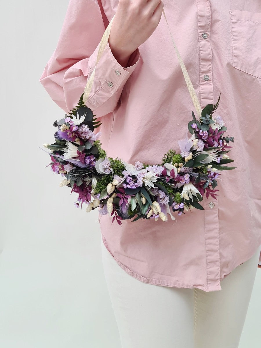 Meisje met bloemenkrans van paarse en groene droogbloemen
