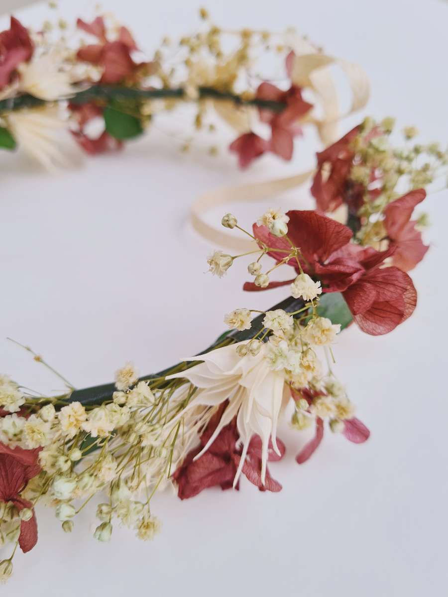 Detailfoto van een handgemaakte bloemenkroon met droogbloemen zoals paarse hortensia, wit gipskruid en groene eucalyptus