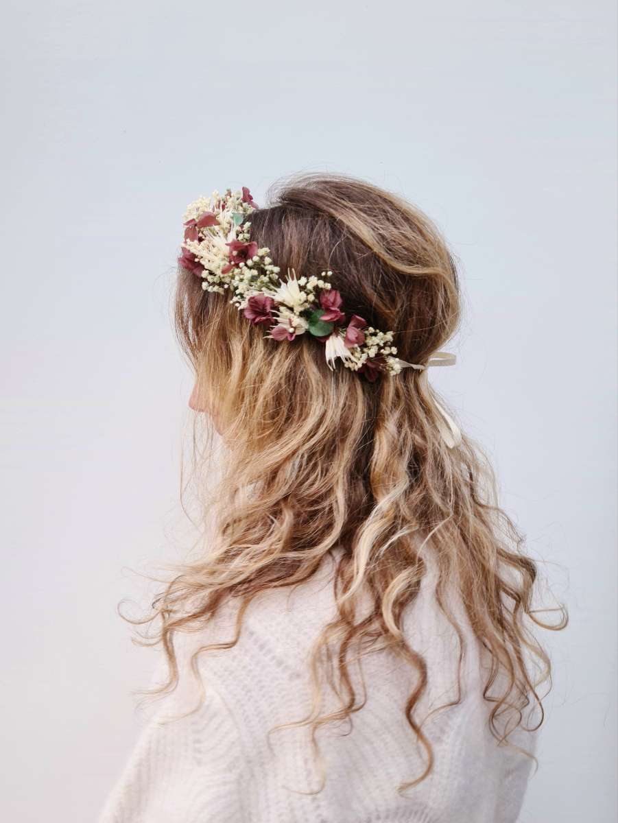 blonde vrouw draagt een weelderige bloemenkrans in het haar met droogbloemen