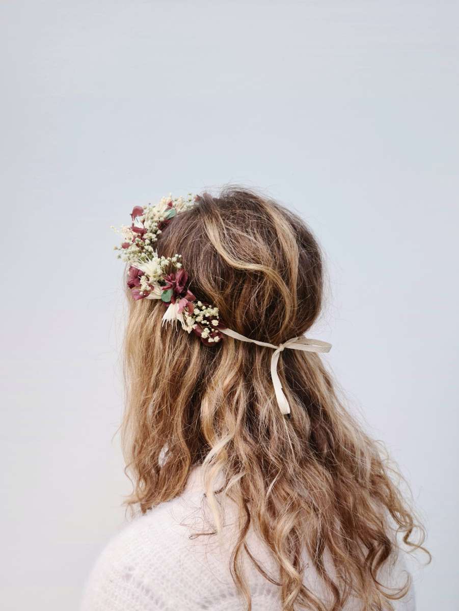 achterkant van een bruid met lange, blonde krullen die een luxueuze en weelderige bloemenkroon van droogbloemen draagt met hortensia, gipskruid en eucalyptus