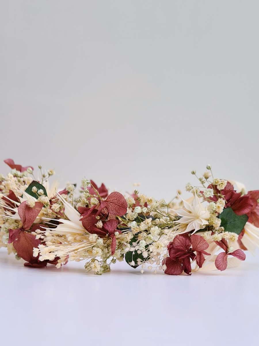 detailfoto van een weelderige bloemenkroon die werd gemaakt met groene, witte en paarse droogbloemen