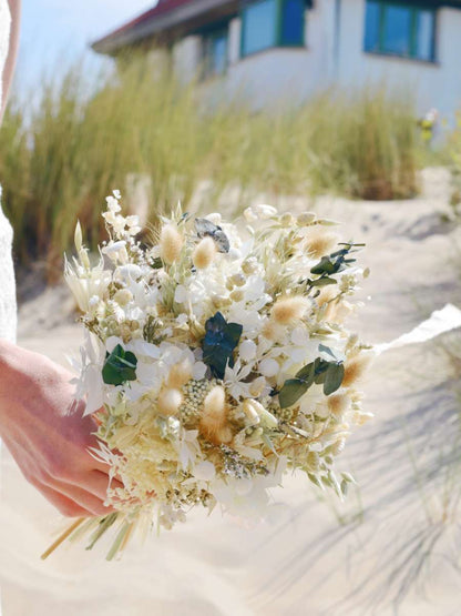 close-up van een klein bruidsboeket van droogbloemen in witte en groene tinten