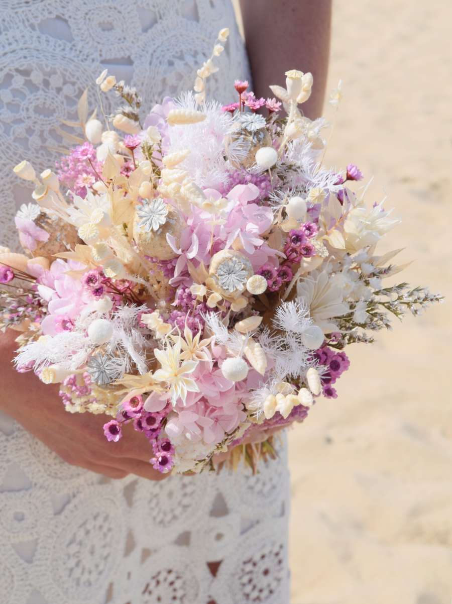 Close-up van een klein en fris bruidsboeket met droogbloemen in lila, pastel en witte tinten