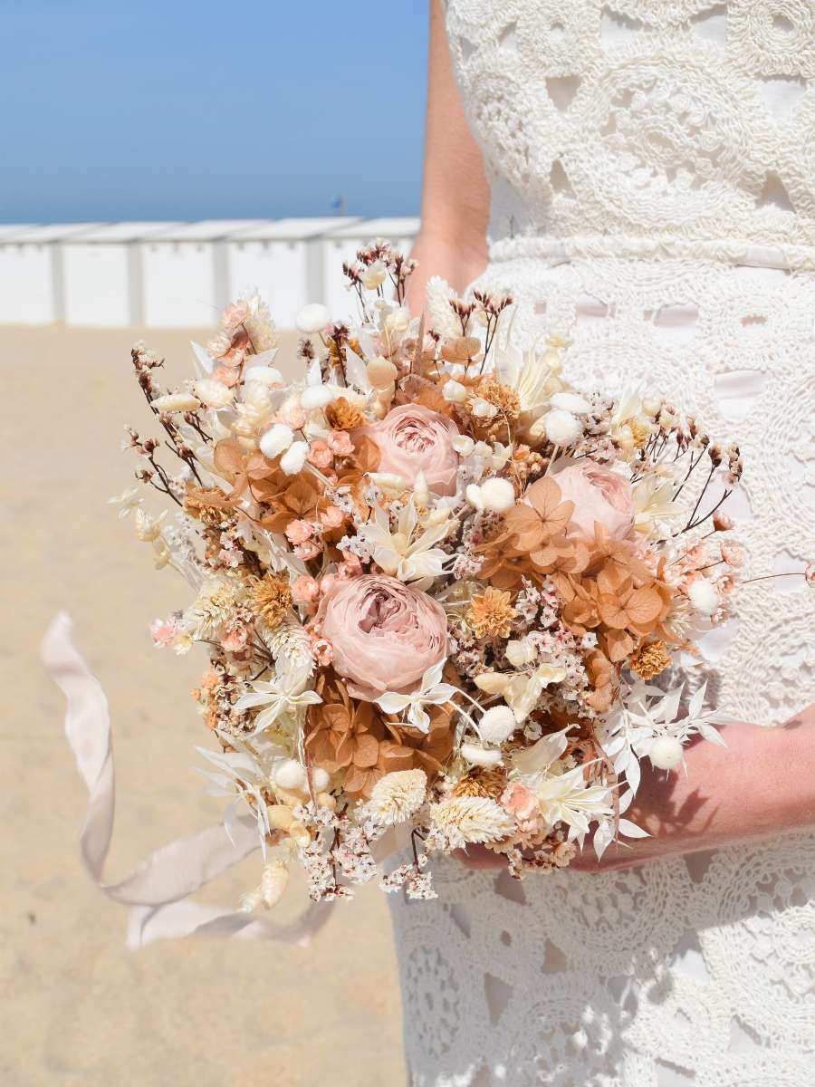 Close-up van een luxueus bruidsboeket van droogbloemen met hortensia, gepreserveerde rozen, ruscus en een lang lint