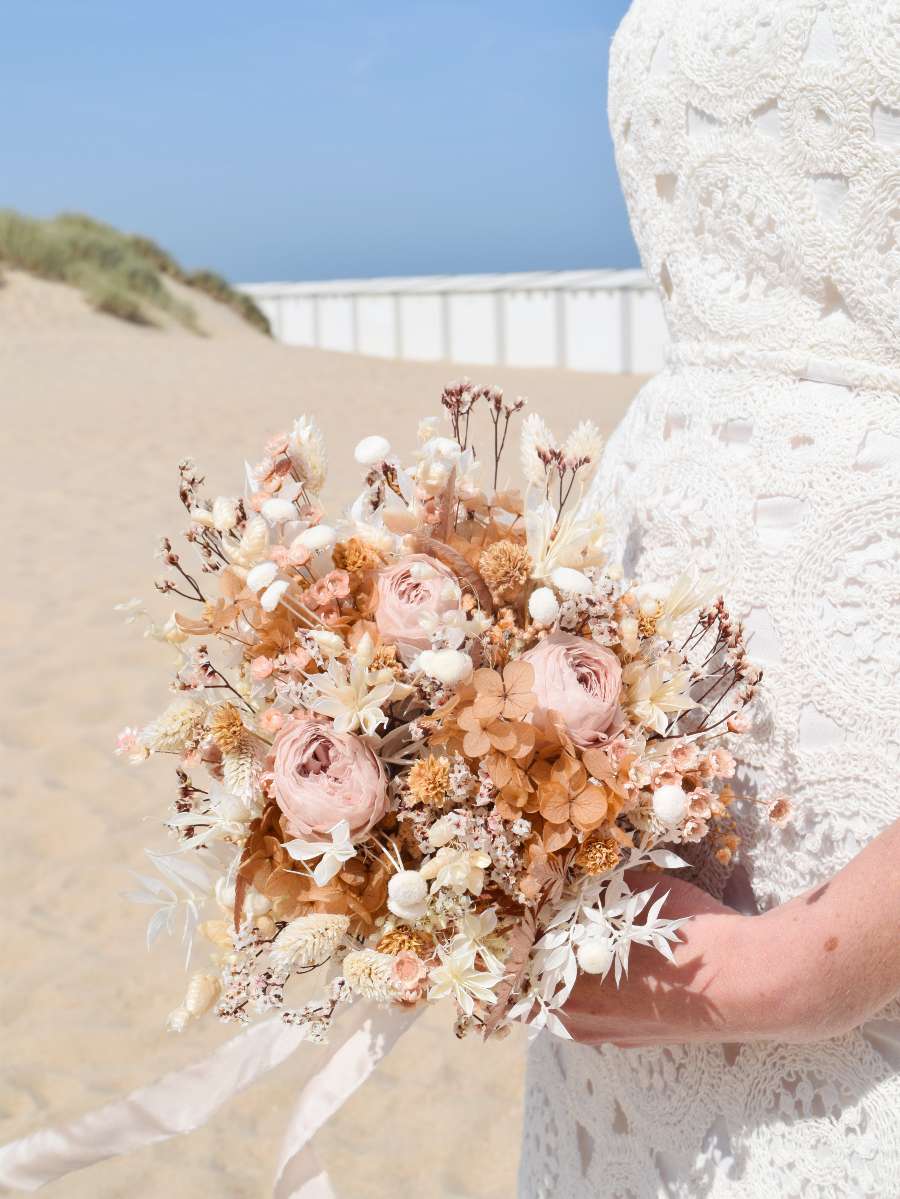 close-up van een klein bruidsboeket dat werd opgemaakt met droogbloemen zoals hortensia, linum, botao en ruscus