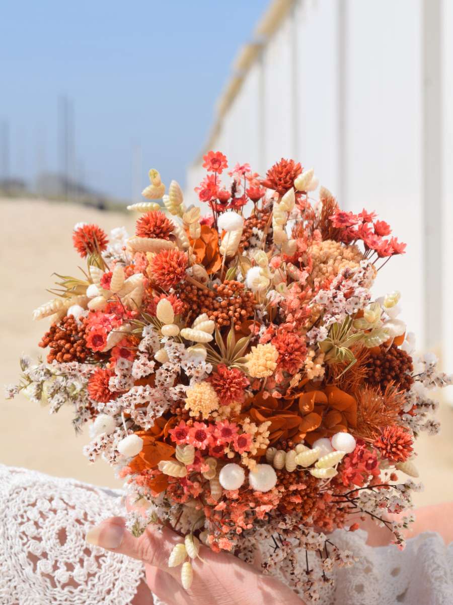 Detailfoto van een trouwboeket in droogbloemen dat bestaat uit oranje hortensia, ruscus rijstbloemen, perzikkleurige achillea, groene breeza, witte botao en nog veel andere droogbloemen