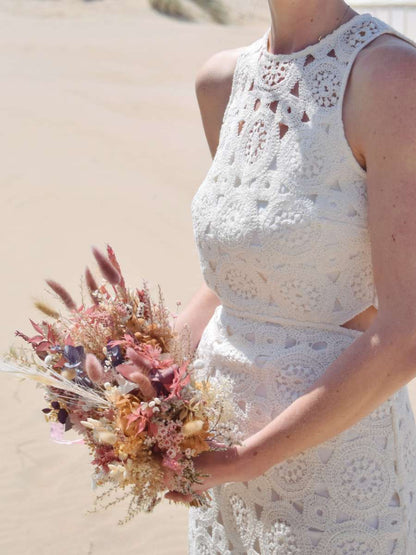 Bruid poseert met een modern trouwboeket van droogbloemen in zachtroze tinten met hortensia, gepreserveerde rozen en bunny tails.