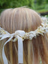 achterzijde van blond meisje die een elegant fijn bloemenkroontje gemaakt van droogbloemen draagt, dichtgebonden met een wit lint