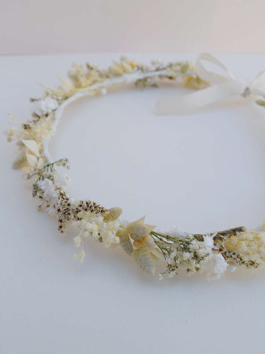 bovenaanzicht van een handgemaakte bloemenkrans van droogbloemen in neutrale en witte tinten die je in het haar kan dragen